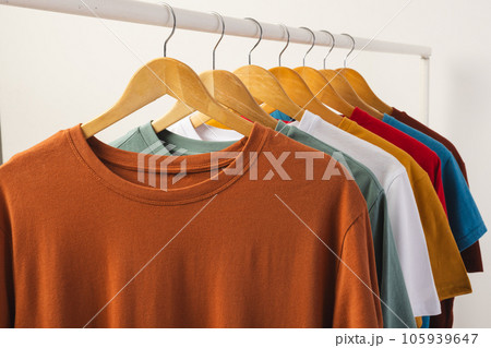 Multi coloured t shirts on hangers hanging from clothes rail and copy space on white background Multi coloured t shirts on hangers hanging from clothes rail and copy space on white background 105939647