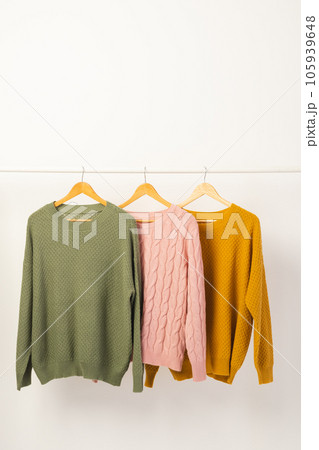 Three sweaters hanging from clothes rail with copy space on white background Three sweaters hanging from clothes rail with copy space on white background 105939648