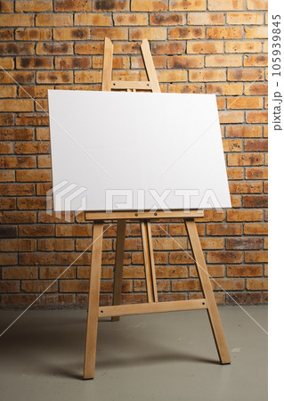 White canvas on wooden easel and copy space on brick wall background White canvas on wooden easel and copy space on brick wall background 105939845