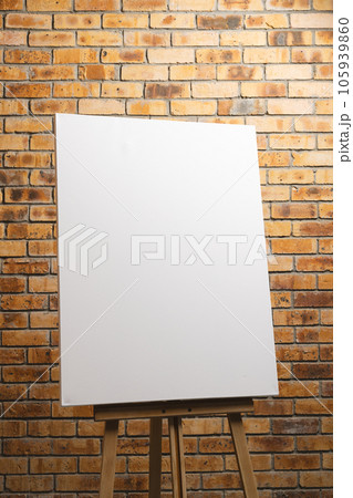 White canvas on wooden easel and copy space on brick wall background 105939860