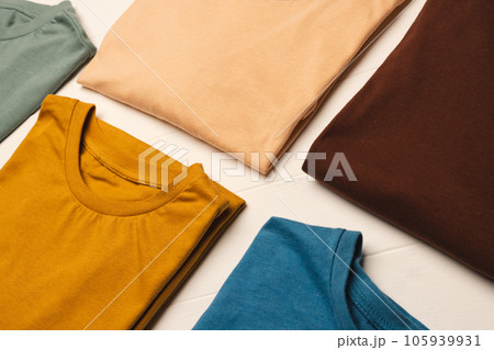 Close up of flat lay of multi coloured t shirts and copy space on white boards background Close up of flat lay of multi coloured t shirts and copy space on white boards background 105939931