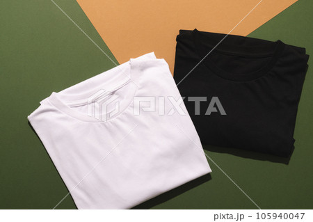 Close up of folded white and black t shirts and copy space on green to orange background Close up of folded white and black t shirts and copy space on green to orange background 105940047