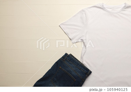 Close up of flat lay of white t shirt, denim trousers and copy space on white boards background Close up of flat lay of white t shirt, denim trousers and copy space on white boards background 105940125