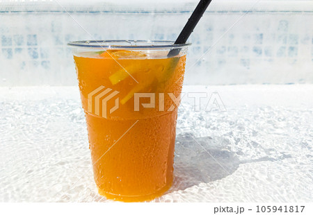 Lemonade with orange and lemon in a glass with a straw by the pool in summer. 105941817