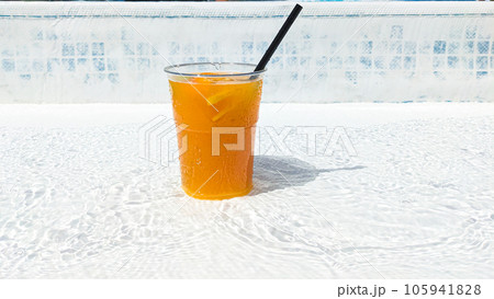 Lemonade with orange and lemon in a glass with a straw by the pool in summer. 105941828