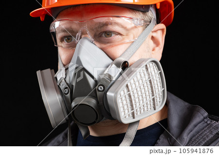 A man wearing a helmet, respirator and goggles on a black background 105941876
