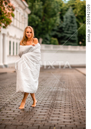 Woman city blanket. Morning in the big city. A blonde woman in a white blanket is enjoying in the city center. Photographed for social media 105942109