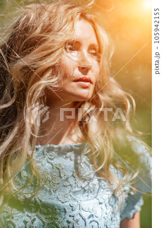Blond garden. Portrait of a blonde in the park. Happy woman with long blond hair in a blue dress. Blond garden. Portrait of a blonde in the park. Happy woman with long blond hair in a blue dress. 105942155
