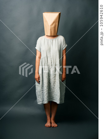 Full length portrait of woman in long dress hiding under empty paper bag 105942610