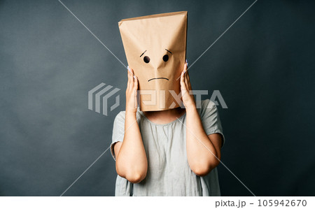 Upset woman with a paper bag on head touching temples, suffering from strong tension headache 105942670