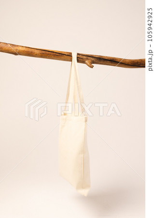 White canvas bag hanging from wooden branch with copy space on white background 105942925