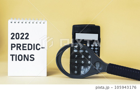 2022 Predictions , text on notebook with calculator and magnifying glass on yellow background 2022 Predictions , text on notebook with calculator and magnifying glass on yellow background 105943176