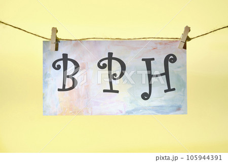 BPH Benign Prostatic Hyperplasia lettering on colored paper hanging in front of a yellow background with a rope and clothespins 105944391