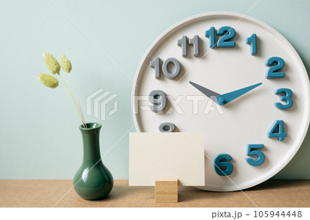 Memo pad holder, clock, vase of dry plant on brown desk. mint wall background. workspace, copy space 105944448