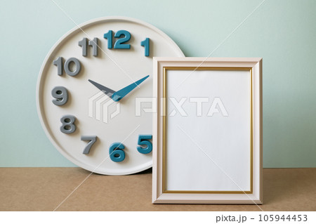 Blank picture frame with clock on brown shelf. mint wall background. copy space 105944453