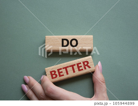 Do better symbol. Wooden blocks with words Do better. Beautiful grey green background. Businessman hand. Business and Do better concept. Copy space. 105944899