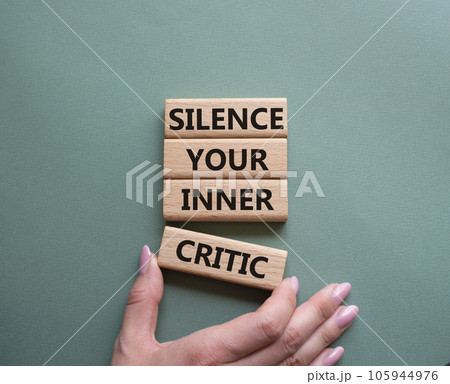 Silence your inner critic symbol. Wooden blocks with words Silence your inner critic. Beautiful grey green background. Businessman hand. Business and Silence your inner critic concept. Copy space. 105944976
