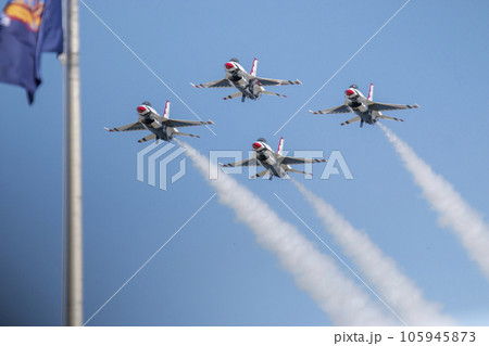 Four F-16 usaf Thunderbirds flying in the diamond formation passing a flag Four F-16 usaf Thunderbirds flying in the diamond formation passing a flag 105945873