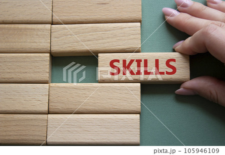 Skills symbol. Concept word Skills on wooden blocks. Businessman hand. Beautiful grey green background. Business and Skills concept. Copy space. Skills symbol. Concept word Skills on wooden blocks. Businessman hand. Beautiful grey green background. Business and Skills concept. Copy space. 105946109