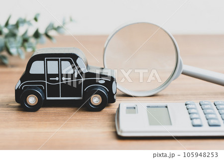 テーブルにおもちゃの車と計算機と虫メガネ 105948253