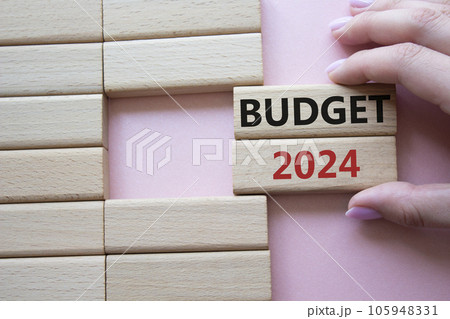 Budget 2024 symbol. Wooden blocks with words Budget 2024. Beautiful pink background. Businessman hand. Business and Budget 2024 concept. Copy space. 105948331
