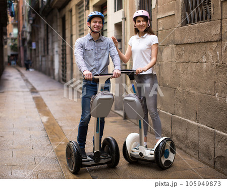 young couple guy and girl walking on segway in streets of european city 105949873