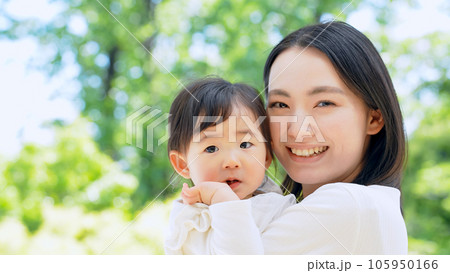 新緑の前で赤ちゃんを抱っこするママ 105950166