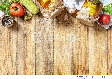 Healthy homemade fermented food. Marinated zucchini (courgette) in tomato sauce on a rustic table. Home economics, autumn harvest preservation. View from above. Copy space. 105951168