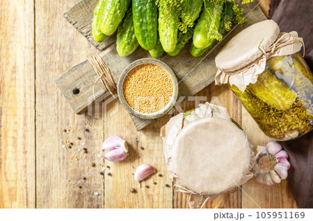 Healthy homemade fermented food. Salted pickled cucumbers with mustard preserved canned in glass jar. Home economics, autumn harvest preservation. View from above. Copy space. 105951169