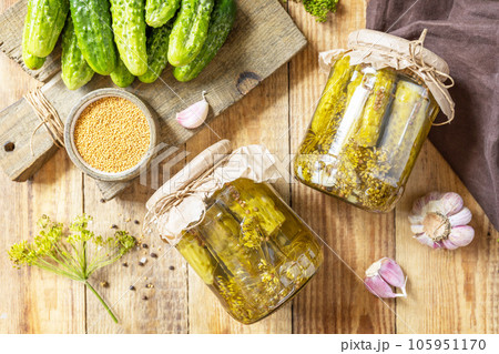 Healthy homemade fermented food. Salted pickled cucumbers with mustard preserved canned in glass jar. Home economics, autumn harvest preservation. View from above. 105951170