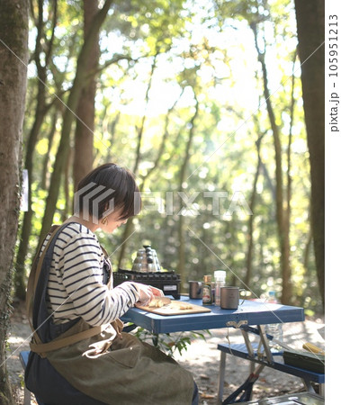 木漏れ日の差すキャンプ場で食材を切る女性 105951213