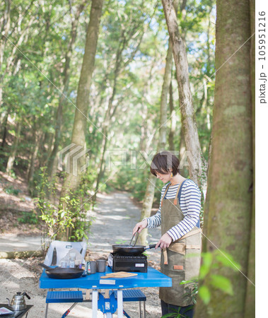 木漏れ日の差すキャンプ場で料理を作る女性 木漏れ日の差すキャンプ場で料理を作る女性 105951216