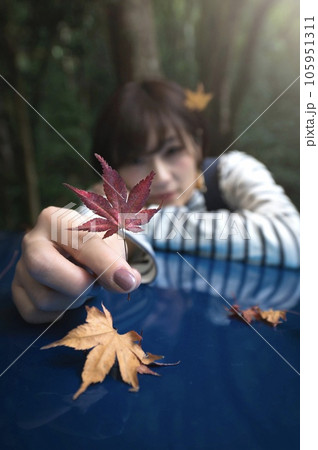 紅葉を一つ摘んで前に出してる女性　紅葉にピント 105951311