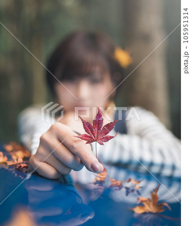 紅葉を一つ摘んで前に出してる女性　紅葉にピント 105951314