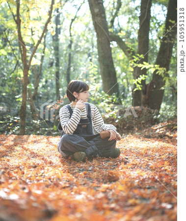 落ち葉の中座って横を向いてるアウトドア女子 105951318