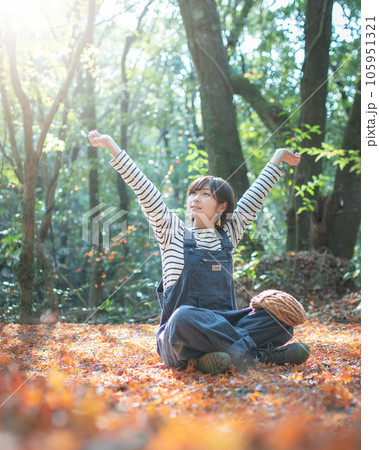 落ち葉の中座って背伸びをしてるアウトドア女子 落ち葉の中座って背伸びをしてるアウトドア女子 105951321