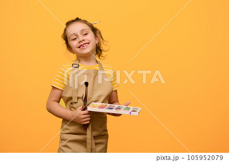 Happy talented inspired little painter girl 6 years old, primary school student with painting tools, smiles at camera 105952079