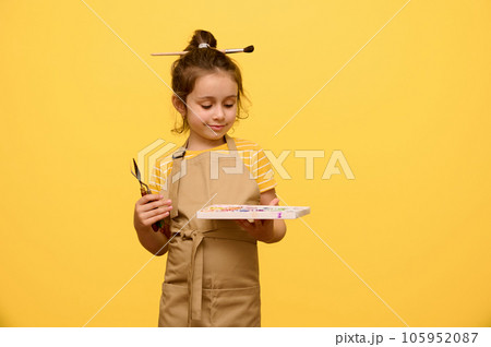 Portrait on yellow background of a cute little kid girl with painting tools, isolated over yellow studio background Portrait on yellow background of a cute little kid girl with painting tools, isolated over yellow studio background 105952087