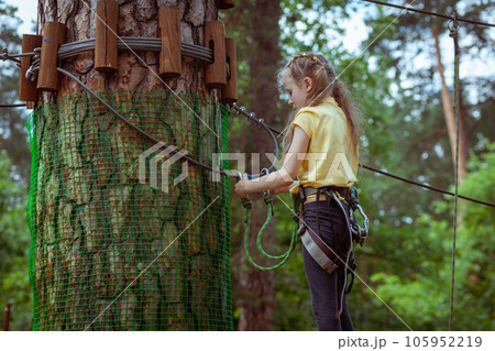 A child in a forest adventure park made of ropes. A child in a forest adventure park made of ropes. 105952219