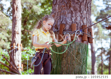 A child in a forest adventure park made of ropes. 105952535