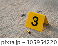 One yellow crime scene evidence marker on the street after a gun shooting brass bullet shell casing 9mm handgun pistol 105954220