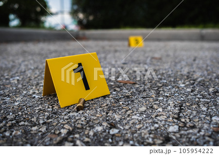 A group of yellow crime scene evidence markers on the street after a gun shooting brass bullet shell casing rifle 105954222