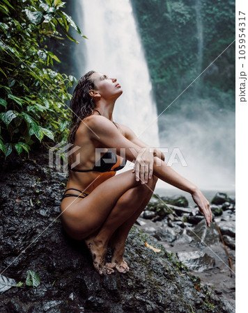 Lady in bikini near powerfull waterfall. Woman relaxing on nature 105954317