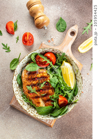 Fresh green salad with grilled chicken fillet, tomatoes, avocado, lemon on light background. Diet Concept. Top view copy space Fresh green salad with grilled chicken fillet, tomatoes, avocado, lemon on light background. Diet Concept. Top view copy space 105954425