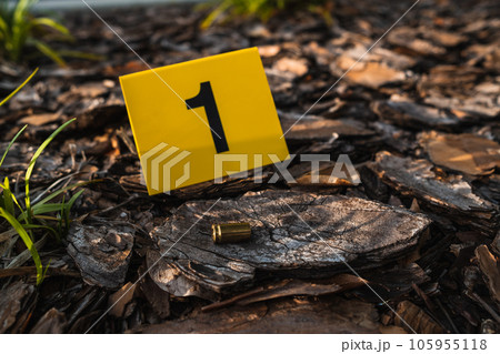 One yellow crime scene evidence marker on the ground after a gun shooting brass bullet shell casing 9mm handgun pistol 105955118