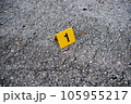 One yellow crime scene evidence marker on the street after a gun shooting brass bullet shell casing 9mm handgun pistol 105955217