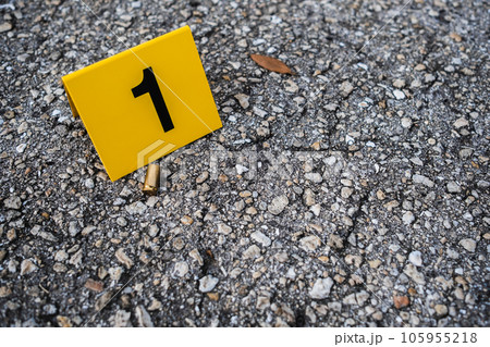 One yellow crime scene evidence marker on the street after a gun shooting brass bullet shell casing 9mm handgun pistol 105955218