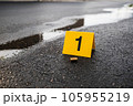 One yellow crime scene evidence marker on the street after a gun shooting brass bullet shell casing 9mm handgun pistol 105955219