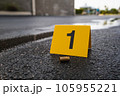 One yellow crime scene evidence marker on the street after a gun shooting brass bullet shell casing 9mm handgun pistol 105955221