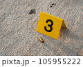 One yellow crime scene evidence marker on the street after a gun shooting brass bullet shell casing 9mm handgun pistol 105955222